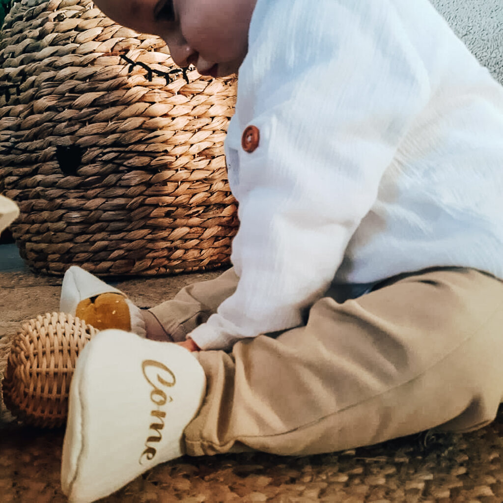 pieds de bébé avec des chaussons en cuir blanc à son prénom