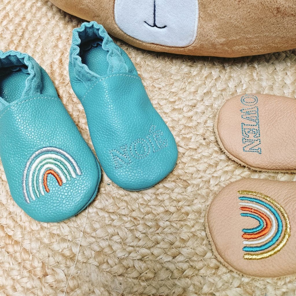 chaussons en cuir vert d'eau pour bébé avec une broderie arc en ciel coloré et le prénom de l'enfant